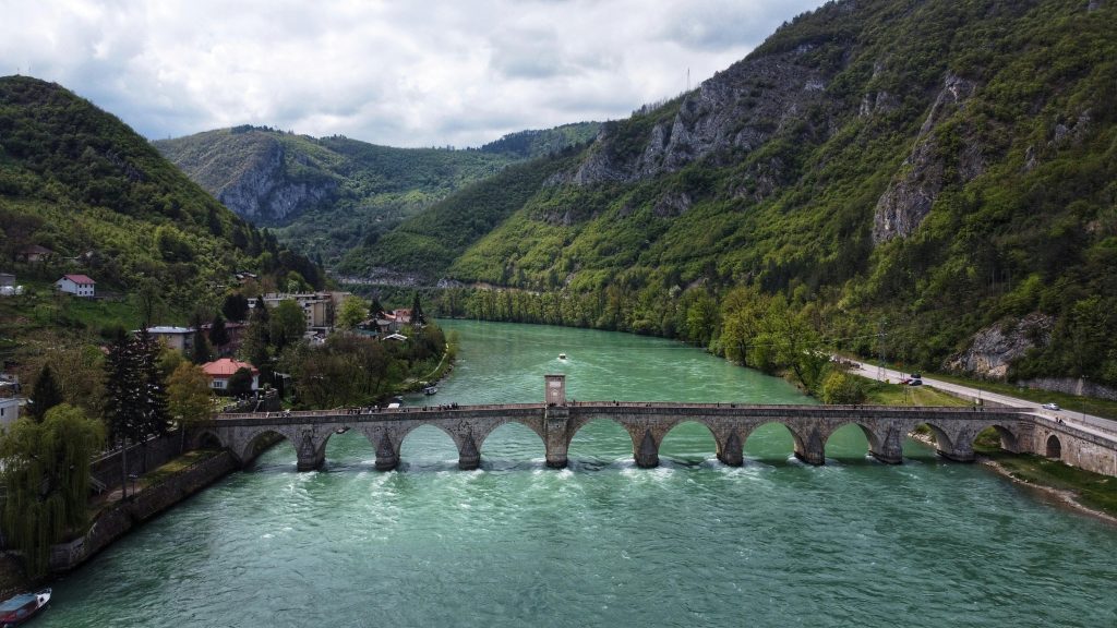 Stunning view of the historic stone bridge spanning a vibrant emerald river in Višegrad, Bosnia.